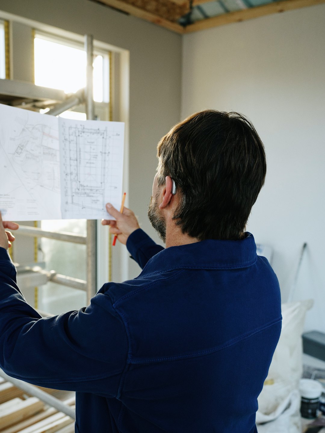 Home Construction worker reviews blueprints in unfinished room.