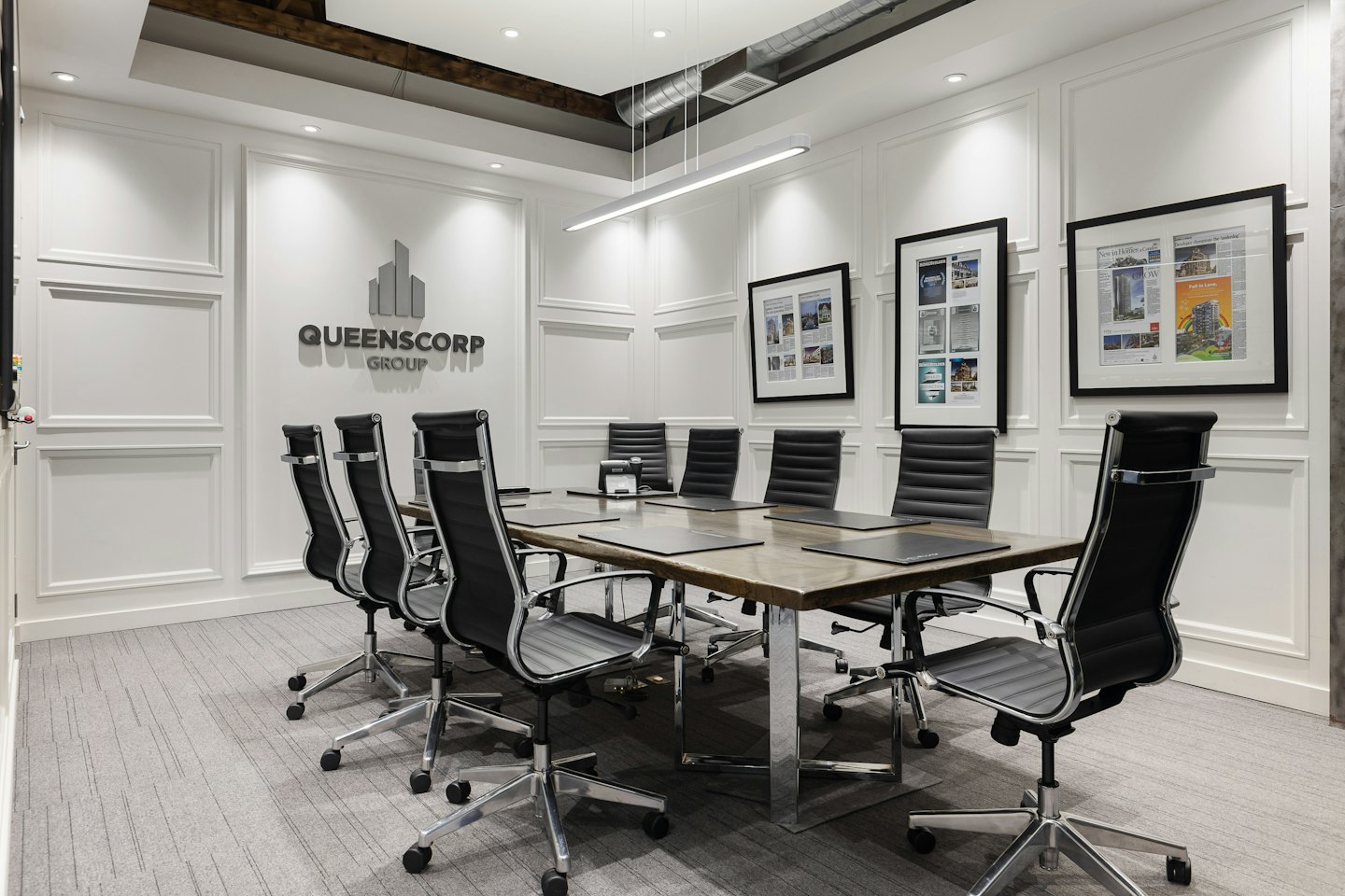 Booking Conference room with long table and Queenscorp Group logo.