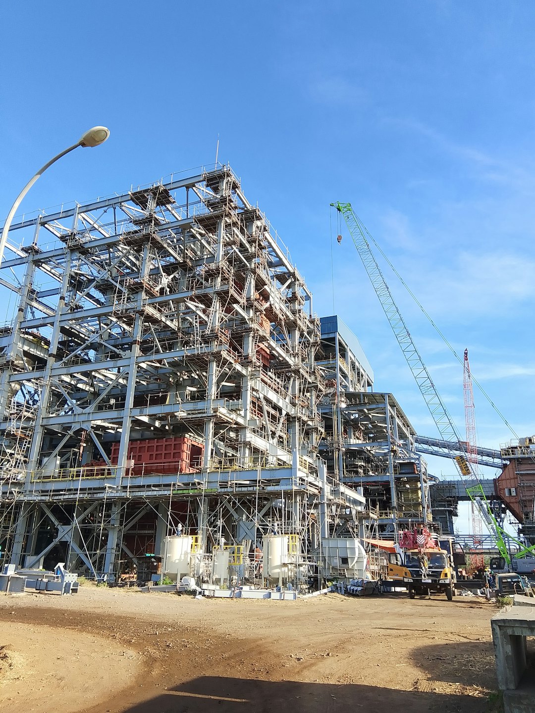 Portfolio Construction workers build a large steel framework structure on site.